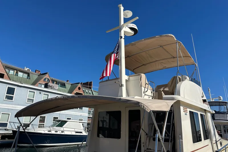 Slide: The Image of 2006 Sabre 42 Fly Bridge yacht docked, featuring a beige canopy and American flag. - 60