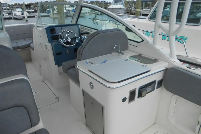 Slide: The Image of 2022 Stingray 269 DC boat interior with helm, seating, and kitchenette at marina. - 4
