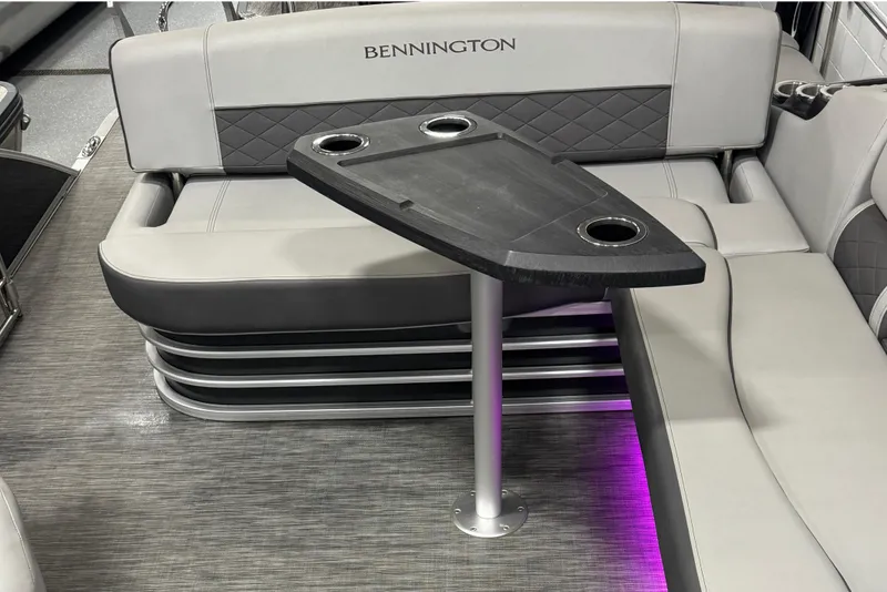 Slide: The Image of 2021 Bennington L 25 Swingback interior with seating and table, featuring cup holders and ambient lighting. - 11