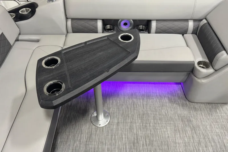 Slide: The Image of 2021 Bennington L 25 Swingback interior with table, cup holders, and ambient lighting. - 25