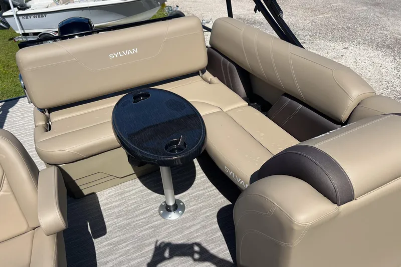 Slide: The Image of 2026 Sylvan Mirage 822 CLZ boat interior with beige seating and a black table. - 14