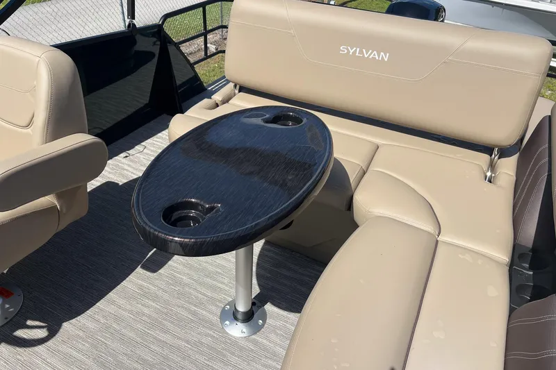 Slide: The Image of 2026 Sylvan Mirage 822 CLZ boat interior with beige seating and oval table. - 15