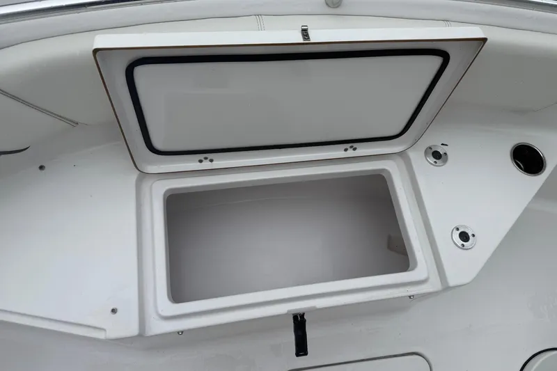 Slide: The Image of 2020 Sportsman Open 232 Center Console boat storage compartment, open lid, white interior. - 11