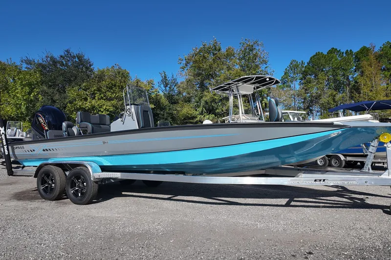 The Image of 2026 Xpress H24B Bay boat on trailer, blue and gray design, parked outdoors. - 0