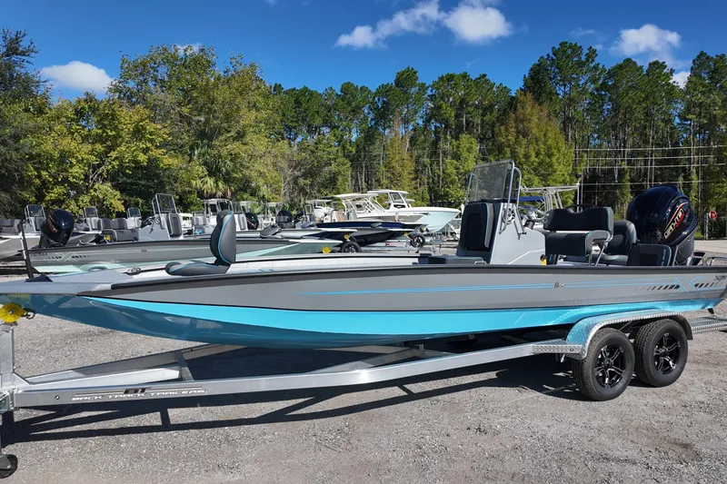 Slide: The Image of 2026 Xpress H24B Bay boat on trailer, parked outdoors under clear blue sky. - 1