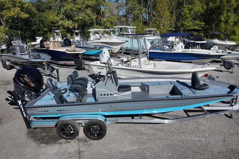 Slide: The Image of 2026 Xpress H24B Bay boat on trailer, surrounded by various boats in a marina. - 2