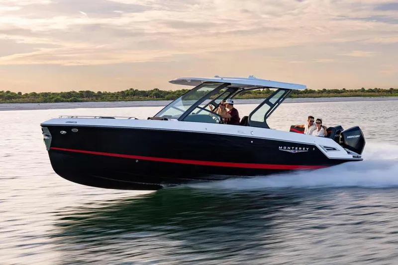 The Image of 2026 Monterey Elite 30 OB boat displayed in a showroom, featuring sleek black and red design. - 0