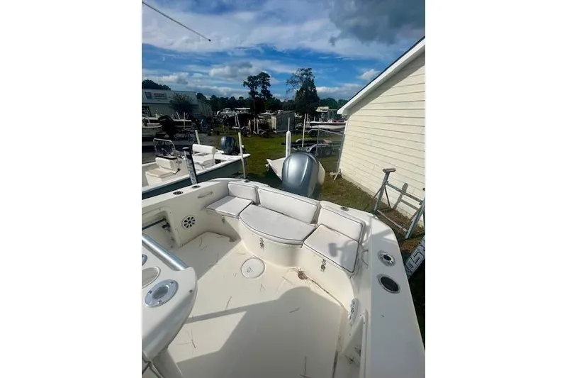 Slide: The Image of 2006 Triton 225 CC boat interior with seating and storage, under a partly cloudy sky. - 7