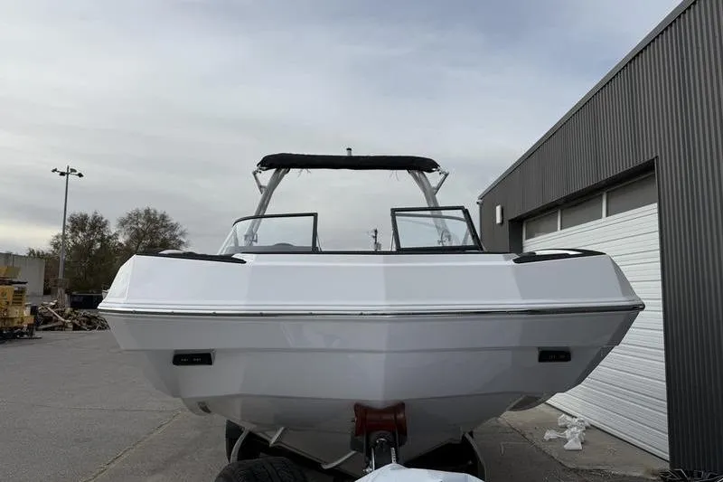 Slide: The Image of 2025 Moomba Max boat, white exterior, parked near a garage, front view. - 3