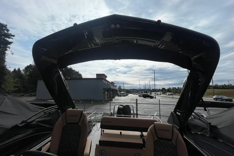 Slide: The Image of 2026 Harris Grand Mariner 250 boat interior with canopy, parked outdoors under cloudy sky. - 16