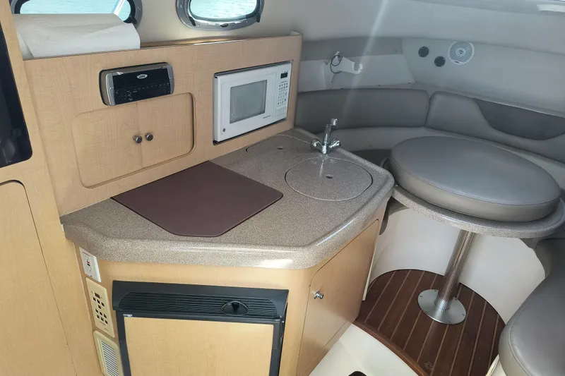 Slide: The Image of 2002 Boston Whaler 295 Conquest cabin with kitchenette, microwave, and seating area. - 13