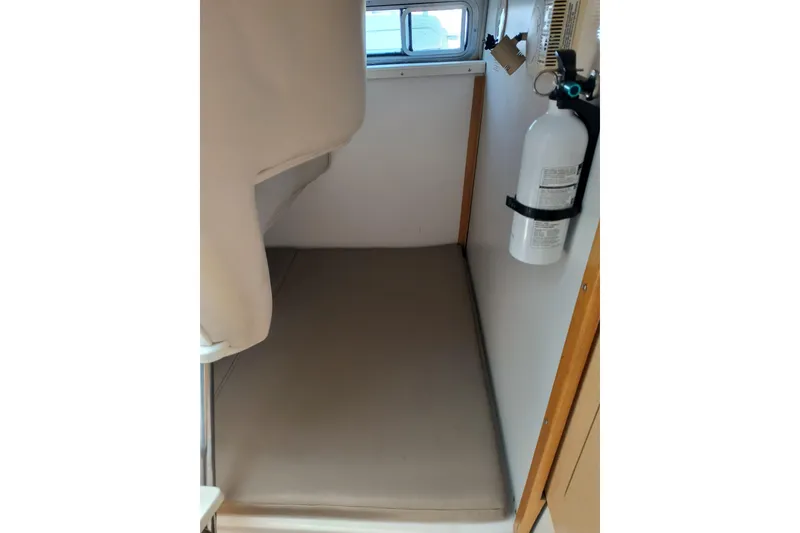 Slide: The Image of 2002 Boston Whaler 295 Conquest cabin interior with fire extinguisher and cushioned seating. - 15