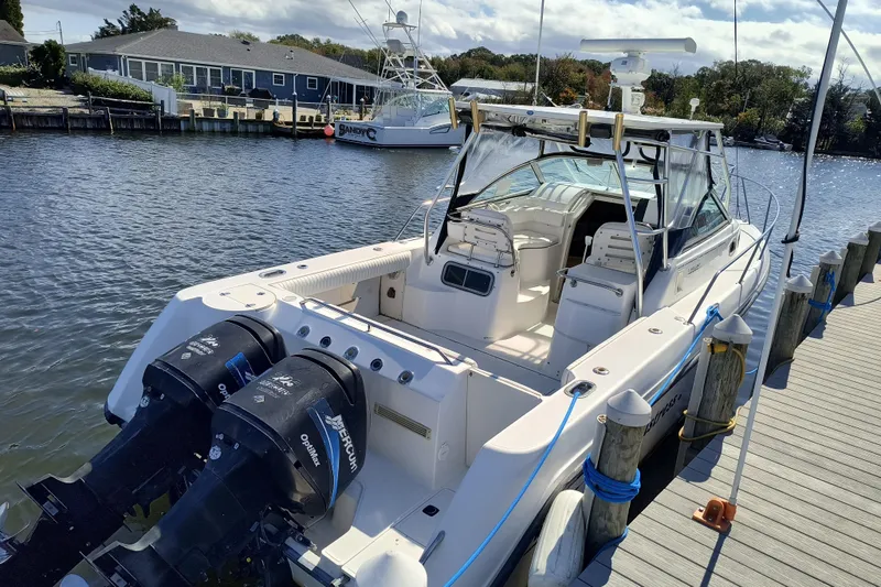 Slide: The Image of 2002 Boston Whaler 295 Conquest docked, featuring dual outboard engines and spacious cockpit. - 2