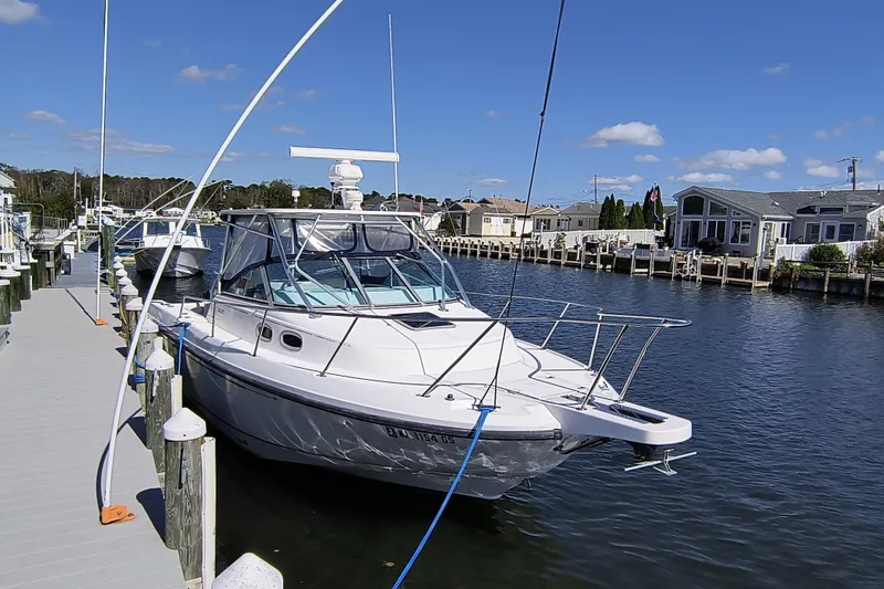 Slide: The Image of 2002 Boston Whaler 295 Conquest docked in a scenic marina under a clear blue sky. - 3