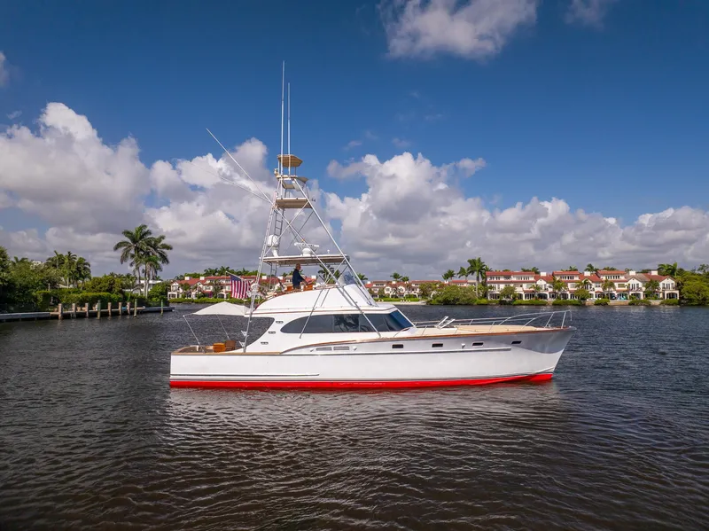 The Image of 1970 Rybovich 54 yacht on calm water, clear sky, luxury waterfront homes in background. - 0