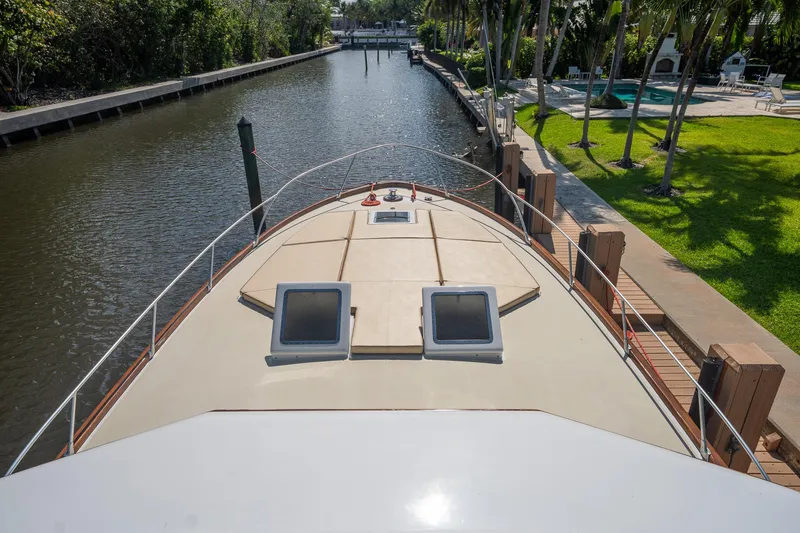 Slide: The Image of 1970 Rybovich 54 yacht docked in a scenic canal with lush greenery. - 10