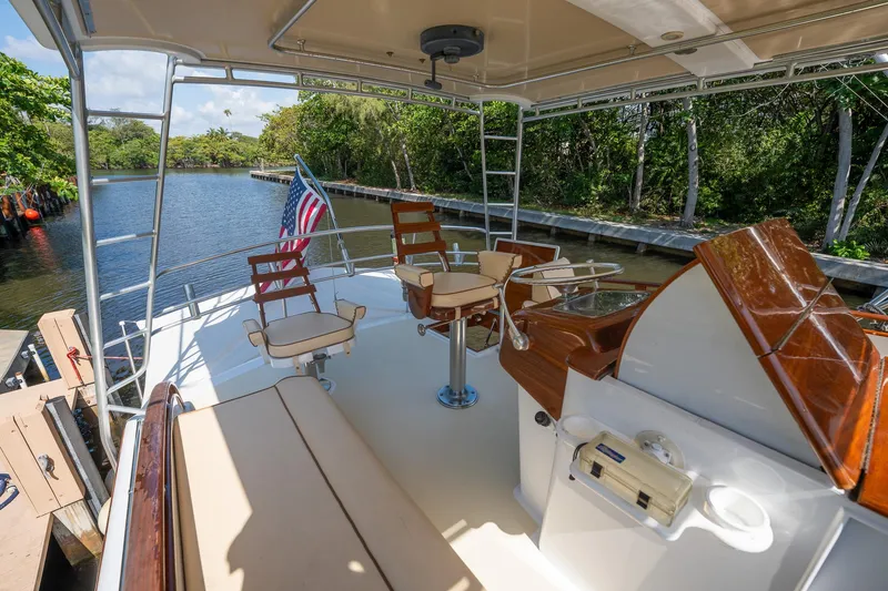 Slide: The Image of 1970 Rybovich 54 yacht deck with seating, helm, and American flag on a serene waterway. - 13