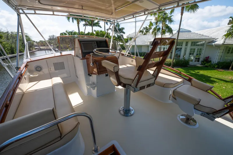 Slide: The Image of 1970 Rybovich 54 yacht helm with seating, surrounded by lush greenery and waterfront view. - 15