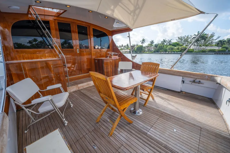 Slide: The Image of 1970 Rybovich 54 yacht deck with wooden furniture and scenic waterfront view. - 18