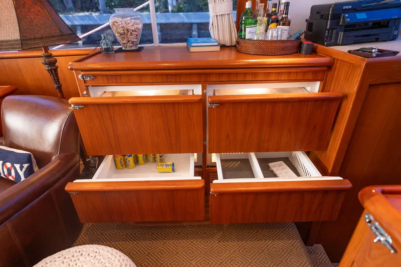 Slide: The Image of 1970 Rybovich 54 yacht interior with open wooden drawers and a well-stocked bar area. - 25