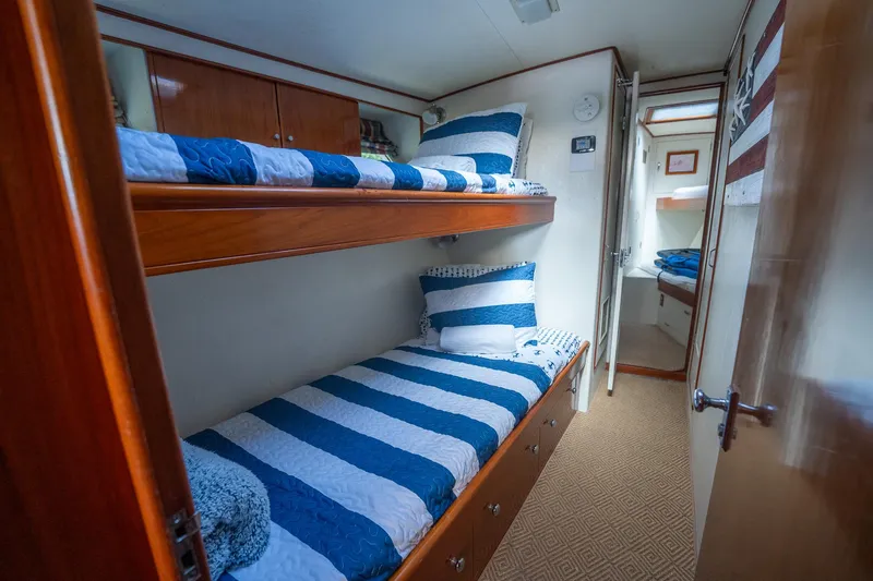 Slide: The Image of 1970 Rybovich 54 yacht cabin with striped bedding and wooden bunk beds. - 28