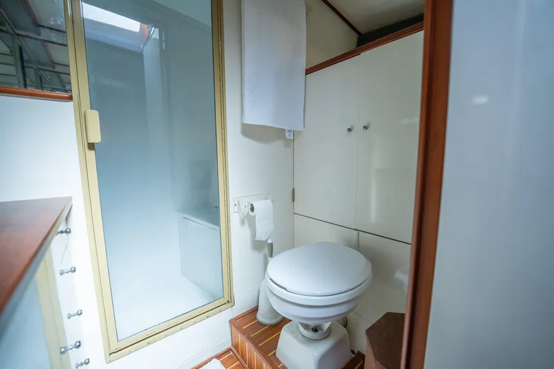 Slide: The Image of 1970 Rybovich 54 yacht bathroom with shower, toilet, and wooden accents. - 33