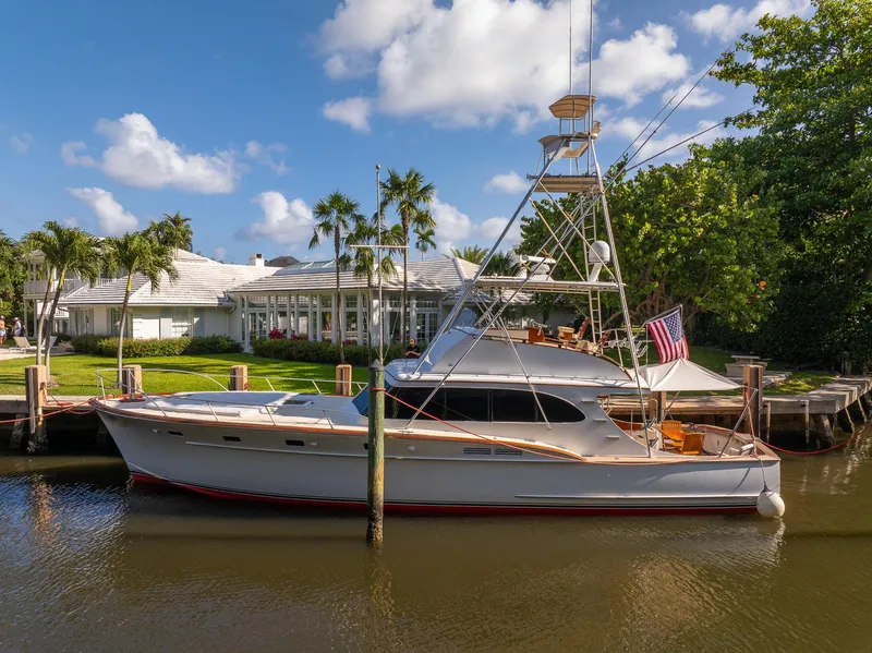 Slide: The Image of Vintage 1970 Rybovich 54 yacht docked by a waterfront home, under a clear blue sky. - 37