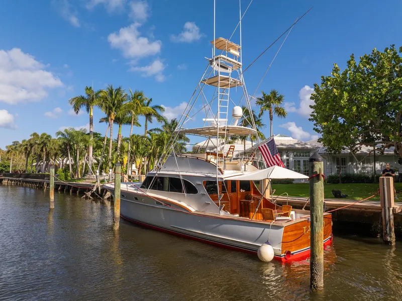 Slide: The Image of 1970 Rybovich 54 yacht docked by palm trees under a clear blue sky. - 38
