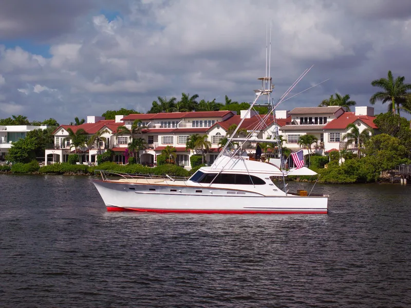 Slide: The Image of 1970 Rybovich 54 yacht cruising near luxury waterfront homes under a partly cloudy sky. - 4
