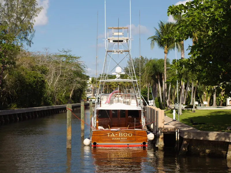 Slide: The Image of 1970 Rybovich 54 yacht docked in a lush, tropical canal setting. - 40