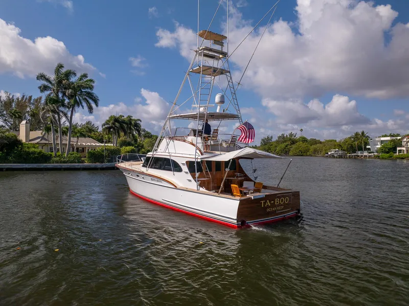 Slide: The Image of 1970 Rybovich 54 yacht on a serene waterway, surrounded by lush greenery and blue skies. - 5