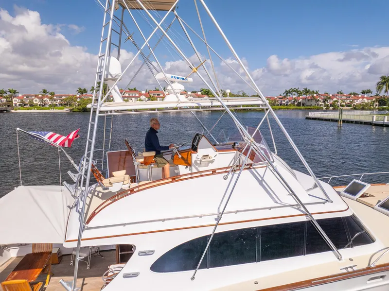Slide: The Image of 1970 Rybovich 54 yacht on water, featuring a flybridge and American flag. - 8