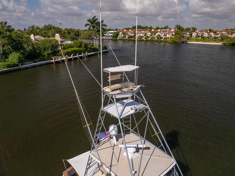 Slide: The Image of 1970 Rybovich 54 boat with tower, docked near lush waterfront homes and palm trees. - 9
