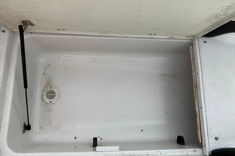 Slide: The Image of Storage compartment of a 2004 Crownline 202 BR boat, featuring a drain and hydraulic lift. - 13