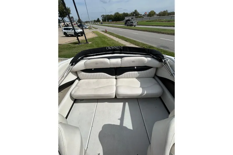 Slide: The Image of 2004 Crownline 202 BR boat interior with white seating, parked near a road. - 17