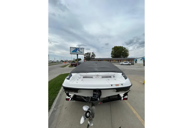 Slide: The Image of 2004 Crownline 202 BR boat with cover, parked near a road under cloudy skies. - 5