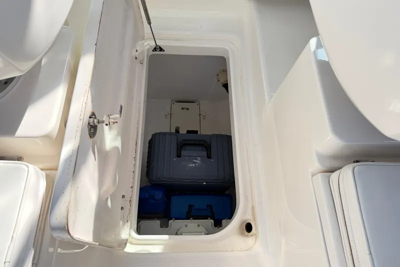 Slide: The Image of Open storage compartment on 2014 Robalo R245 Walkaround boat, containing equipment and supplies. - 15