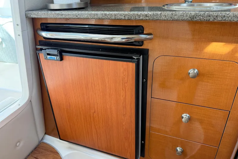 Slide: The Image of 2014 Robalo R245 Walkaround interior with wooden cabinetry and compact fridge. - 25