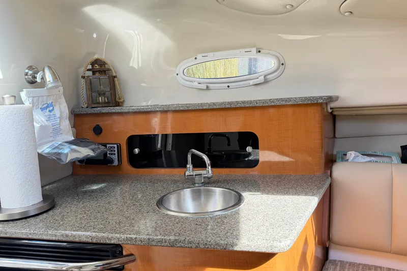 Slide: The Image of 2014 Robalo R245 Walkaround boat interior with kitchenette, sink, and window. - 26