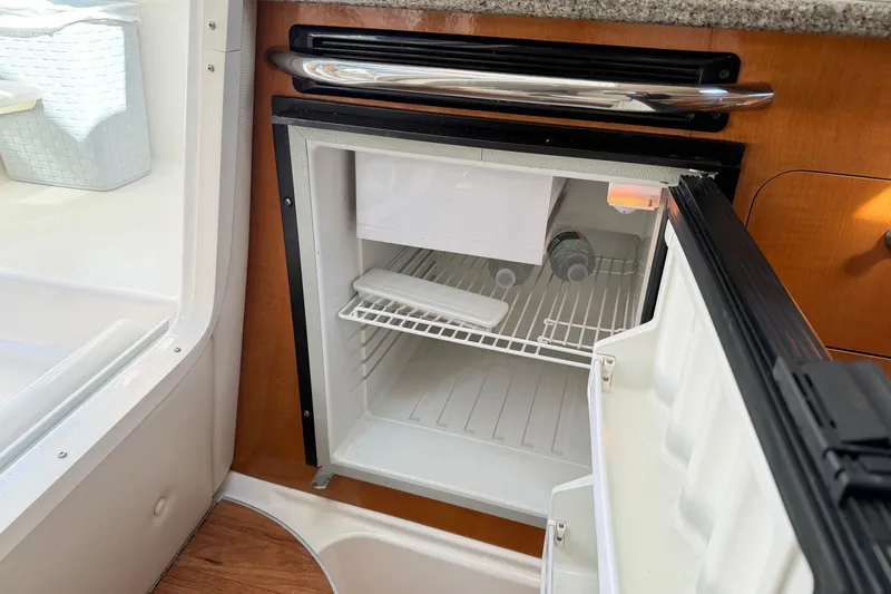 Slide: The Image of Open mini fridge inside 2014 Robalo R245 Walkaround boat, showing interior shelves. - 27