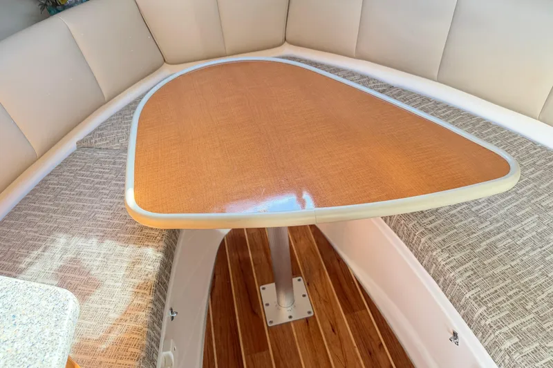 Slide: The Image of 2014 Robalo R245 Walkaround cabin interior with wooden table and cushioned seating. - 30