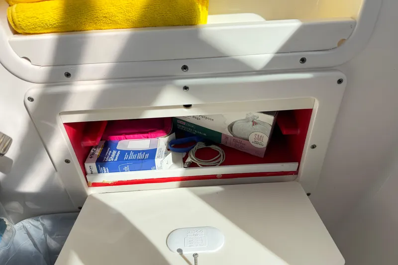 Slide: The Image of Storage compartment on a 2014 Robalo R245 Walkaround boat with various supplies. - 35