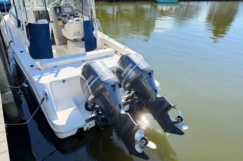 Slide: The Image of 2014 Robalo R245 Walkaround boat with twin Yamaha outboard engines docked on calm water. - 49