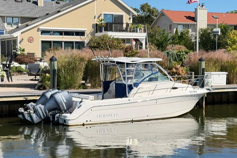Slide: The Image of 2014 Robalo R245 Walkaround boat docked near waterfront homes. - 50