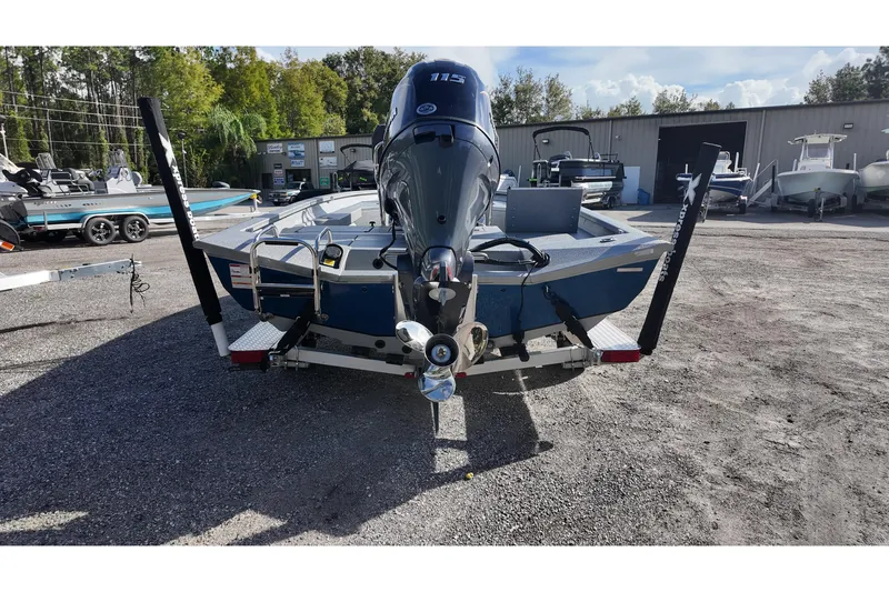Slide: The Image of 2026 Xpress H20B Bay boat with outboard motor, parked on gravel lot. - 14