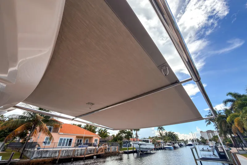 Slide: The Image of 2015 Beneteau Gran Turismo 49 yacht with extended sunshade, docked by a canal. - 6