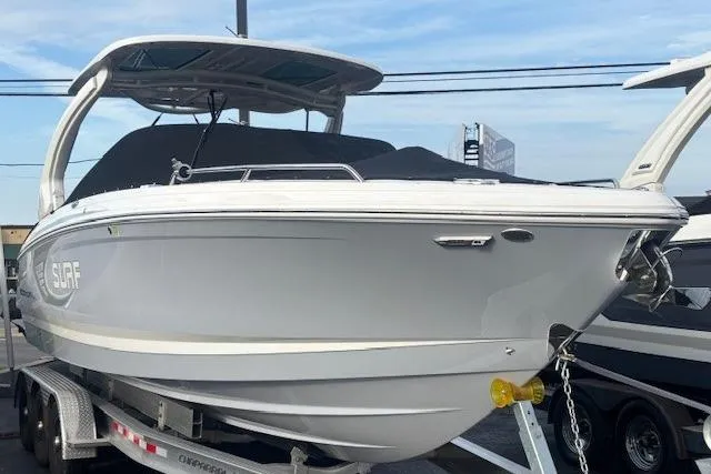 Slide: The Image of 2024 Chaparral 30 Surf boat on trailer, sleek design, white hull, covered cockpit. - 48