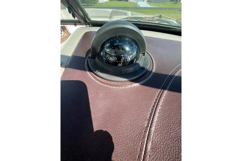 Slide: The Image of Compass on 2012 Sea Ray 250 SLX dashboard, brown leather surface, sunny day. - 13