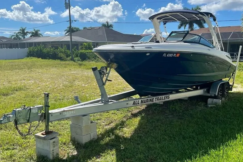 Slide: The Image of 2012 Sea Ray 250 SLX boat on trailer, parked on grass under blue sky. - 16