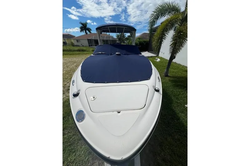 Slide: The Image of 2012 Sea Ray 250 SLX boat with blue cover, parked on grass under a clear sky. - 17